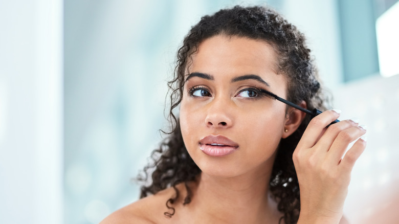 A woman applying mascara to her eyelashes