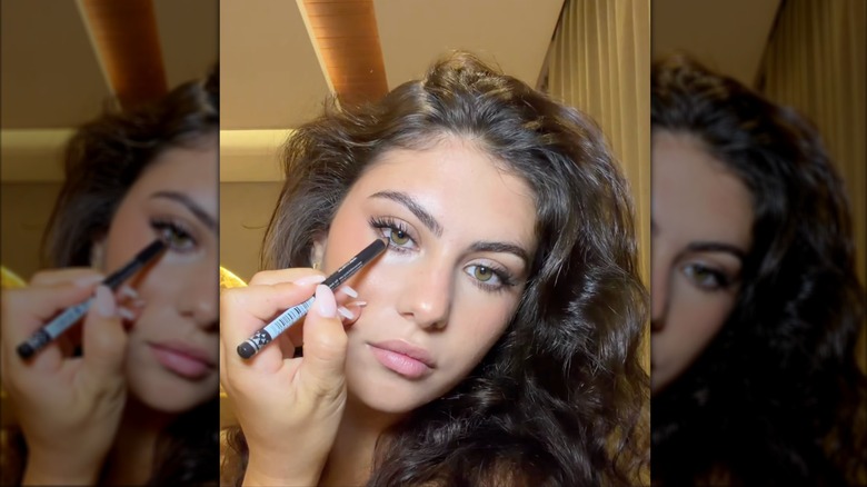 A woman applying charcoal eyeliner in a makeup video on Instagram