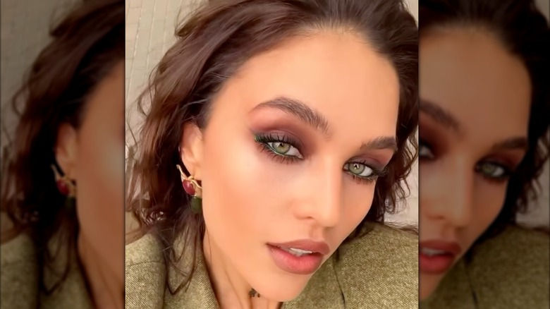 A woman wearing burgundy eyeshadow and green eyeliner with black