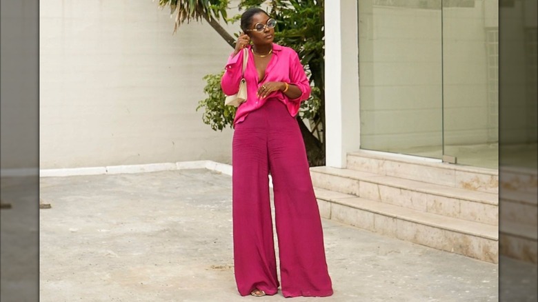 A woman posing while wearing a hot pink top and deep magenta pants