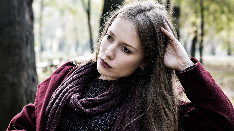 Pale woman outside in the woods wearingm burgundy clothes