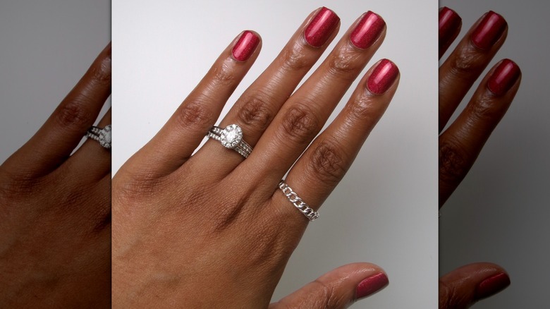 Open hand showing cherry red nails with a hint of sparkle against a white background