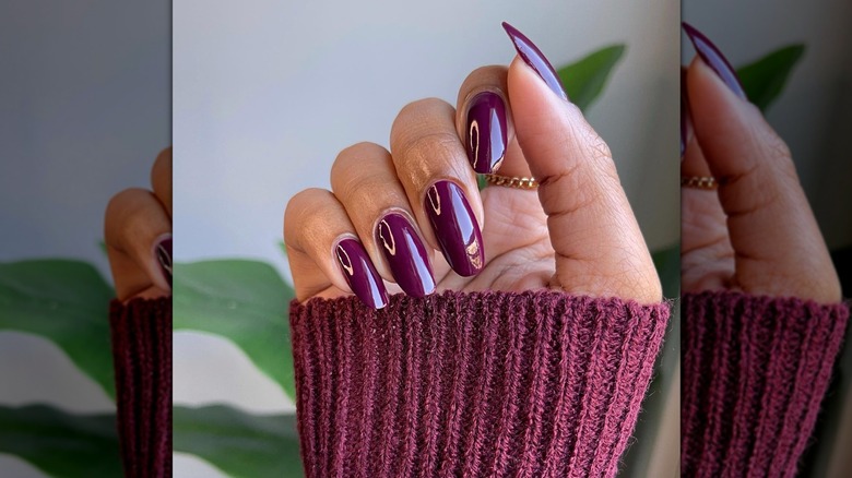 Loosely closed hand showing a dark plum nail polish with a glossy finish