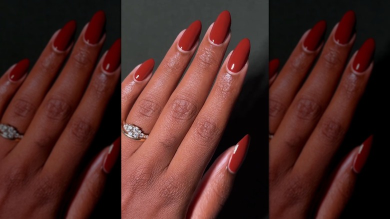 Open hand showing terracotta nails with a round shape against a dark grey background