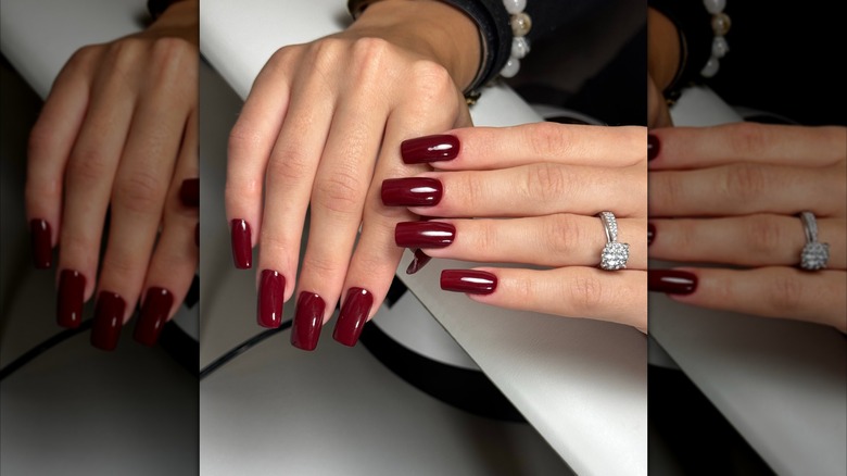 A woman showcases her burgundy manicure