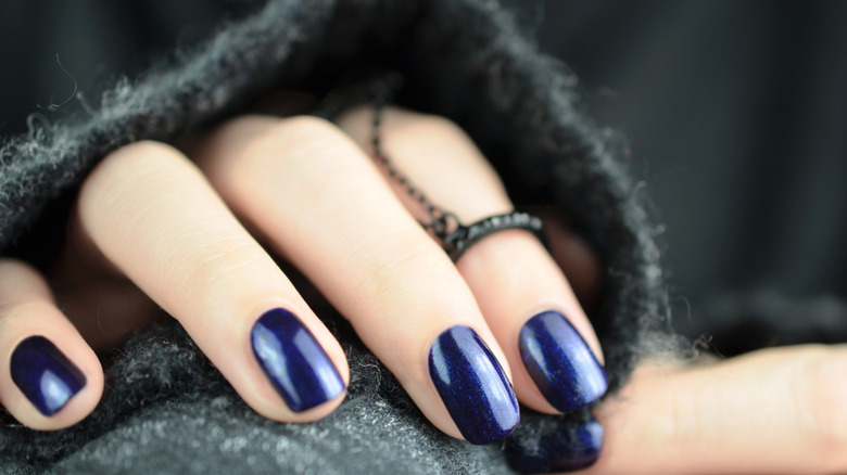 A woman showcasing a navy blue manicure
