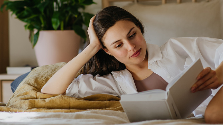 Woman lying in bed reading a book