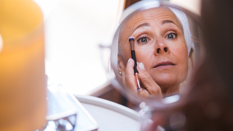 Woman applying eyeshadow to top lid with double-sided eyeshadow brush