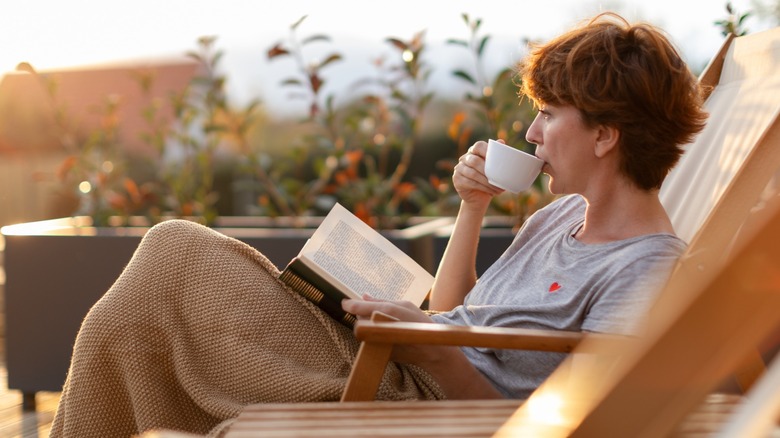 A woman reading a book and sipping tea