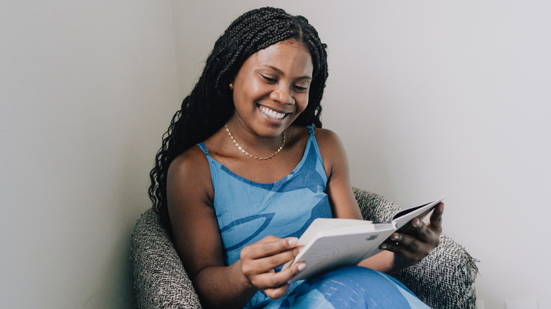 Woman sits in an armchair and reads a book