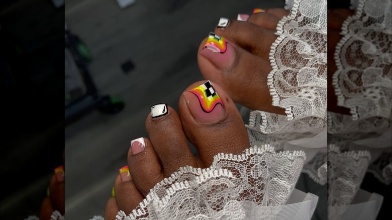 A woman with black and white detailing and colorful designs on a pedicure