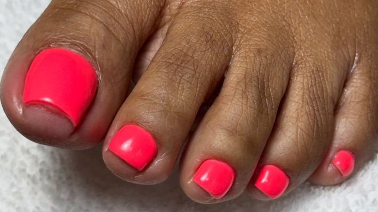 A foot with a bright coral pedicure