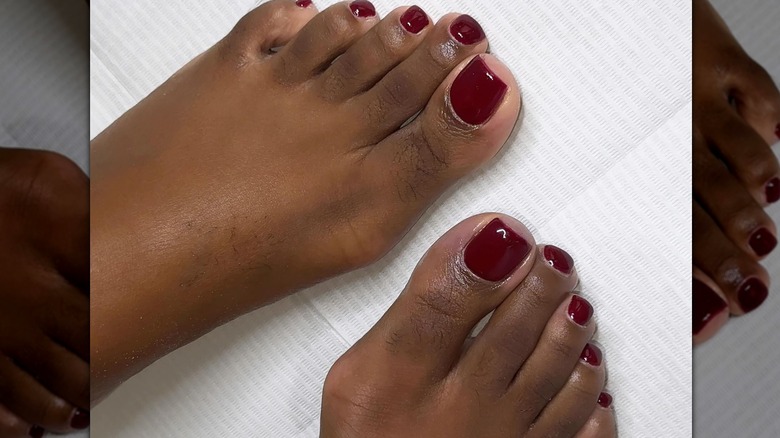 Two feet with a burgundy pedicure