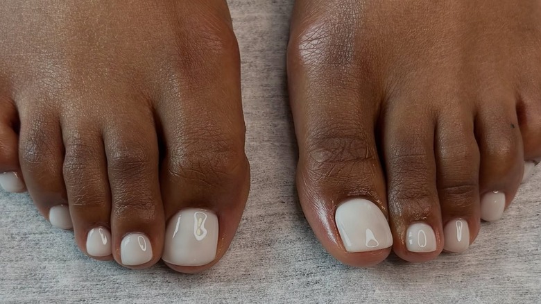 Two feet with a milky white pedicure