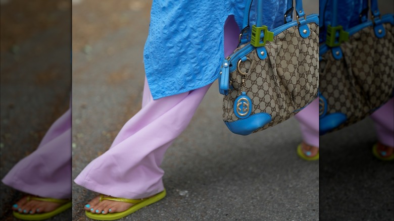 women walking in purple trouser with green flipflops and blue toe colour