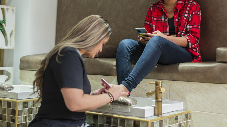 manicurist filing client's toenails