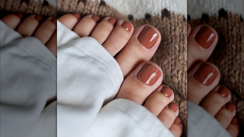 Feet with painted toenails peeking out of white trouser