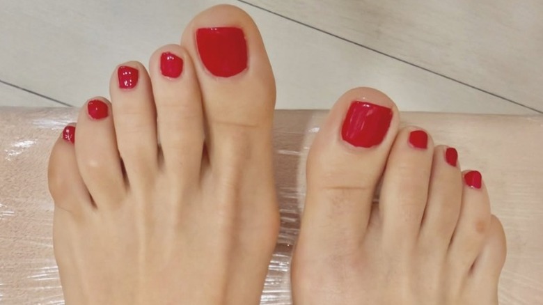 Two feet with a cherry red pedicure