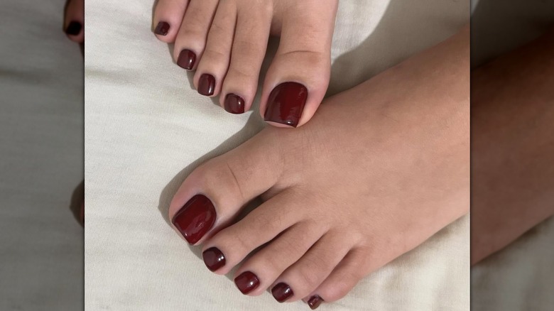 Two feet with a deep berry color pedicure