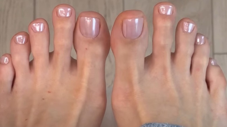 Two feet with a light pink chrome pedicure