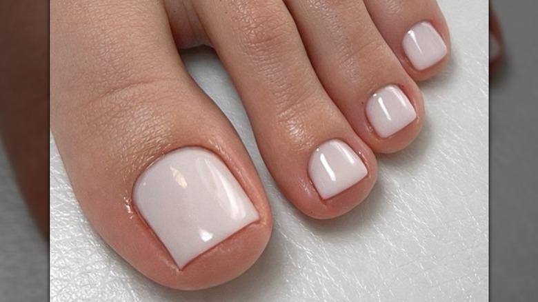 A foot with a milky white pedicure