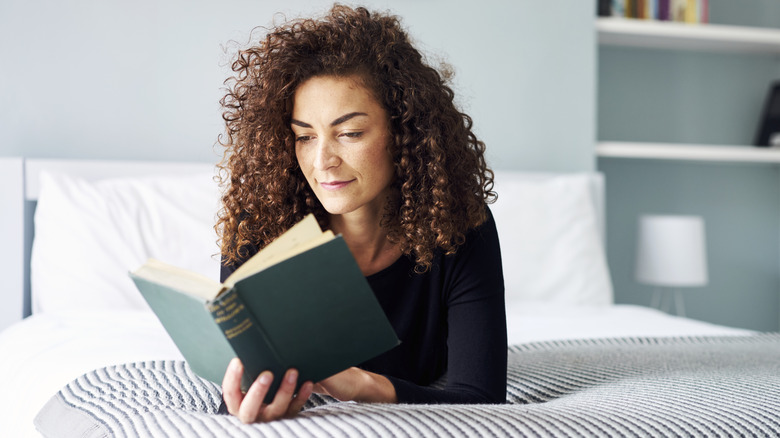 A woman lying on bed reading a book
