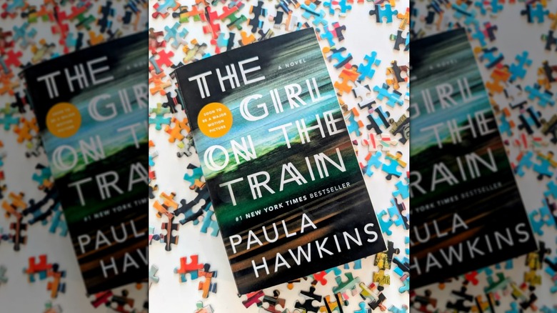 A copy of the book "The Girl on the Train" laying on top of colorful puzzle pieces
