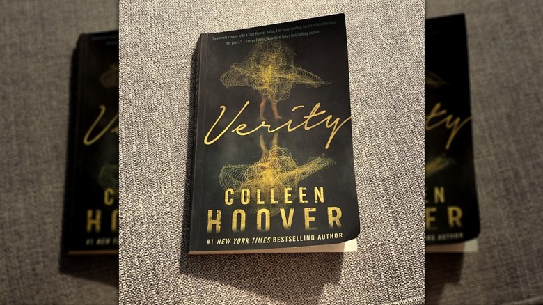 A copy of the novel "Verity" resting on a gray upholstered surface
