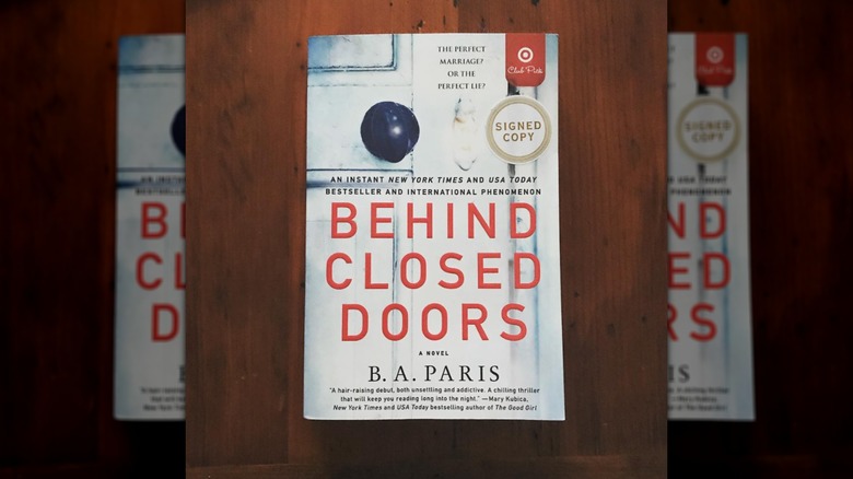 A copy of the novel "Behind Closed Doors" sitting on a wooden table