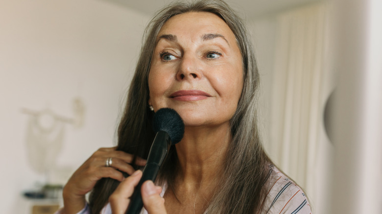 Older woman applying makeup