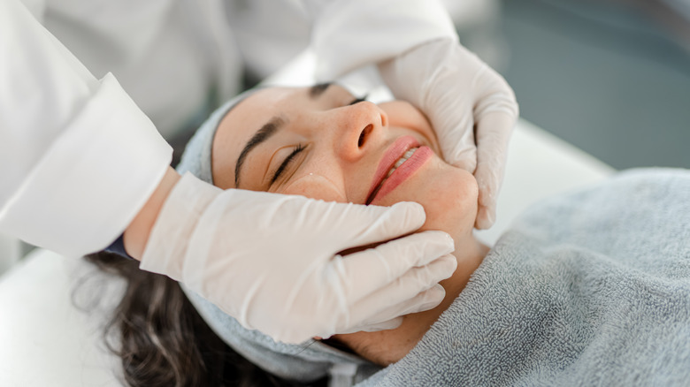 A woman getting a skin treatment from a person with latex gloves on