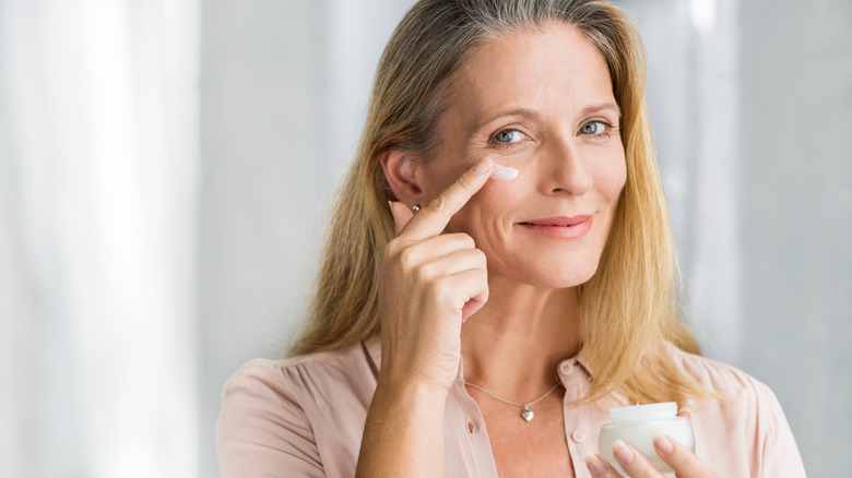 A mature woman applying cream to her skin