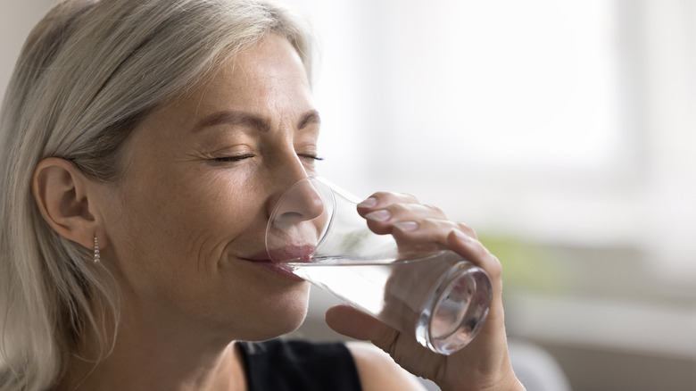 A mature woman drinking a glass of water