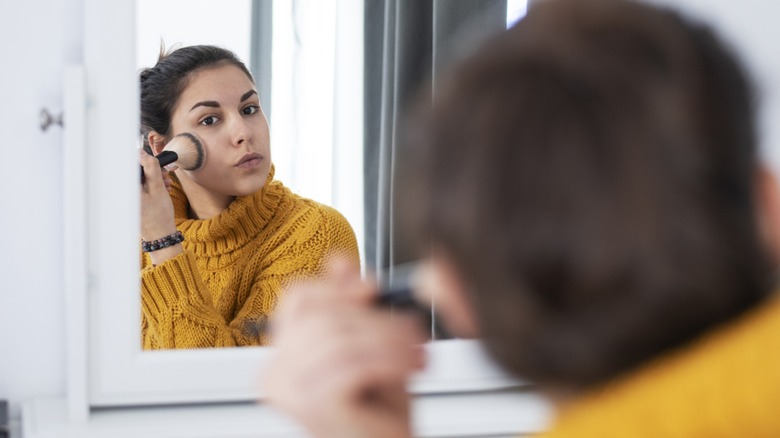 A woman applying powder in the mirror
