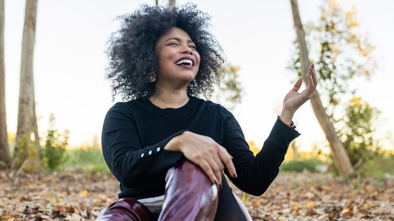 A woman wearing berry lipstick while holding fall leaves