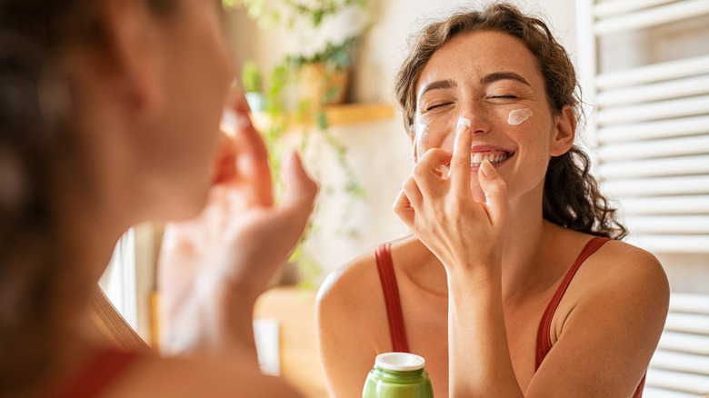 woman applying cream to face