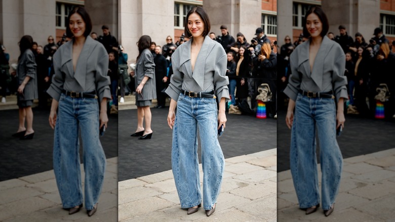 A woman standing outside, wearing barrel jeans with a gray shirt and mules