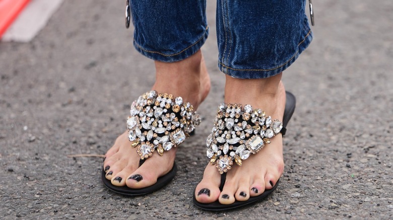 A woman wearing stovepipe jeans with embellished flipflops