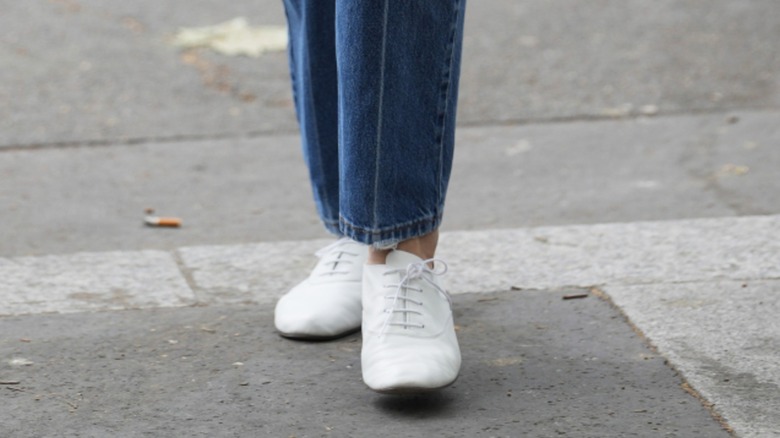 A woman wearing stovepipe jeans with understated white sneakers