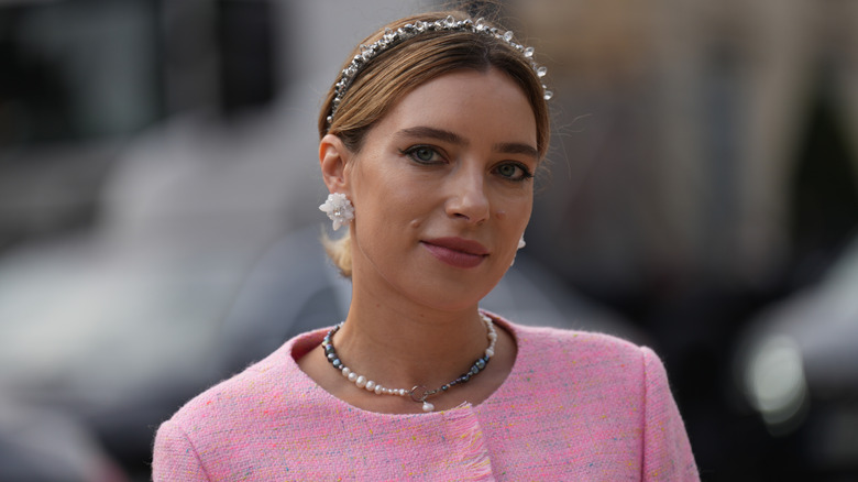 A woman in a pink jacket with a sparkly headband