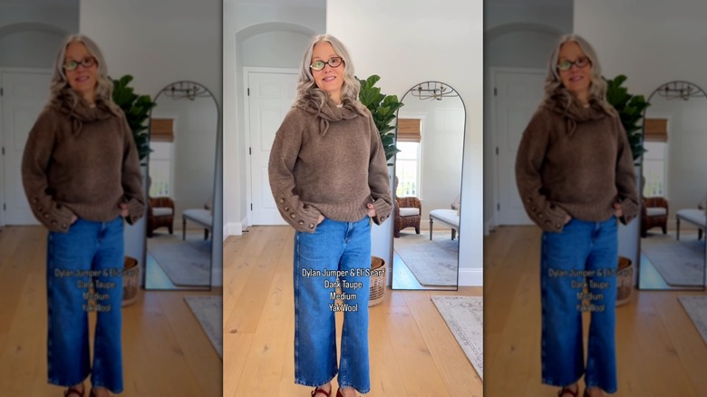 A woman wearing a brown knit and cropped jeans