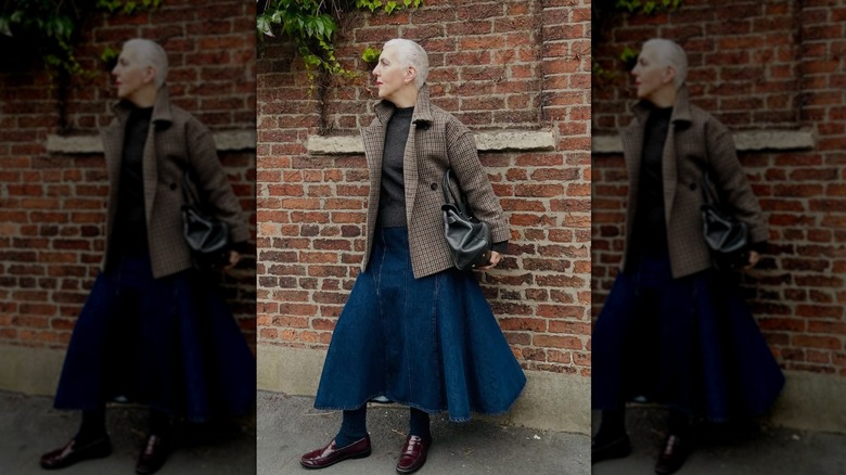 A mature woman wearing a dark wash denim skirt and patterned blazer