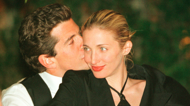 John F. Kennedy Jr. sitting behind Carolyn Bessette-Kennedy and kissing her cheek