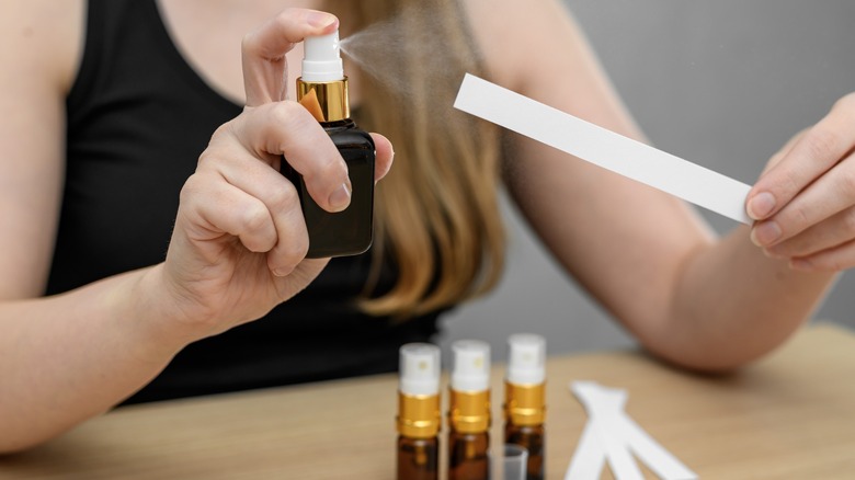 A woman spraying fragrance onto fragrance sample cards