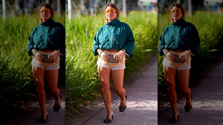 A woman wearing beige lace trimmed shorts with a green jacket