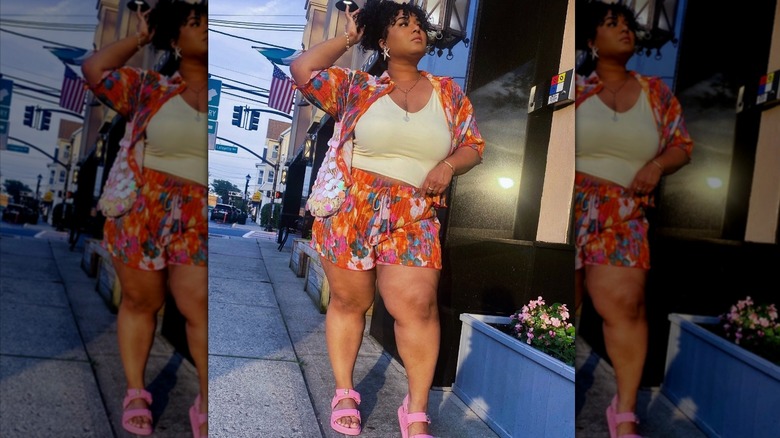 A woman wearing a colorful co-ord, including pull up shorts, and pink sandals