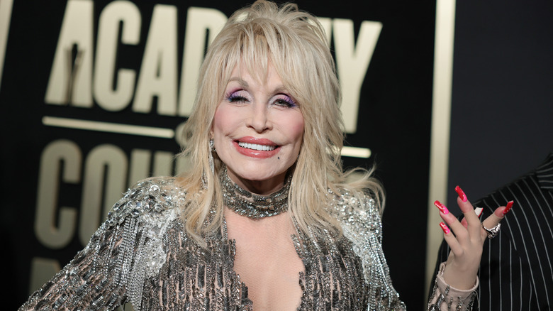 Dolly Parton smiling with her hand up at the Academy of Country Music Awards