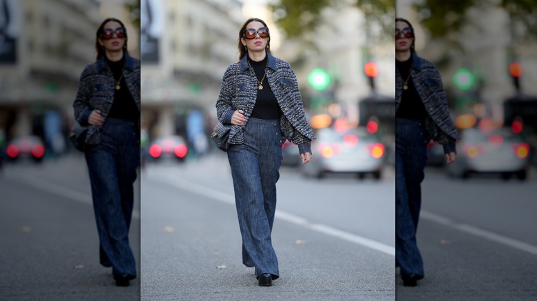 A woman walking down the street in a blue tweed jacket over a black turtleneck and blue jeans