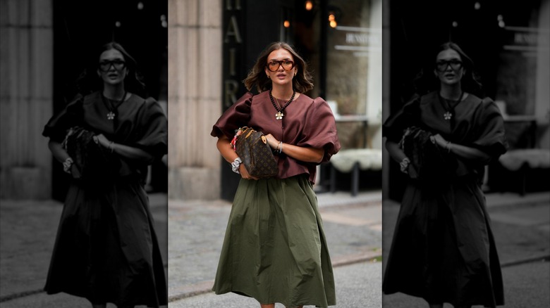 A woman walks about town carrying a purse