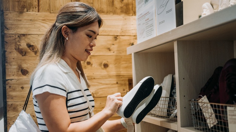 A woman looking at a pair of flat shoes in a store
